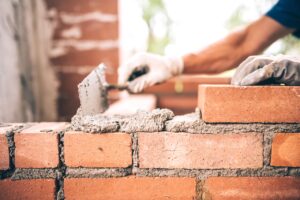 mason laying mortar between bricks