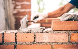 mason laying mortar between bricks