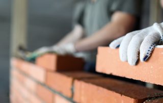 A mason using bricks in construction.