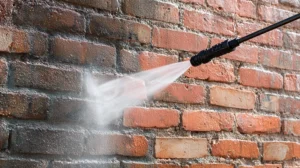 Pressure washing a brick wall. Intense spray removes dirt and grime.